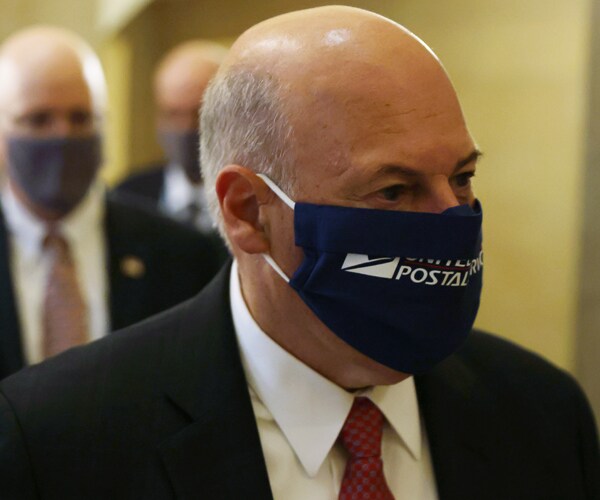 postmaster general louis dejoy walks in the us capitol while wearing a mask that reads us postal service