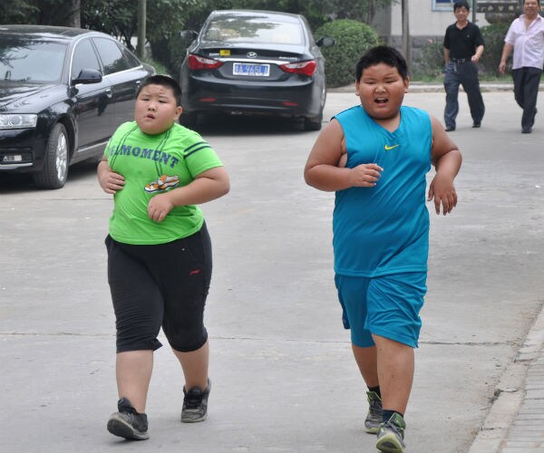 young boys running, one in a green shirt and the other in teal nike shirt and shorts