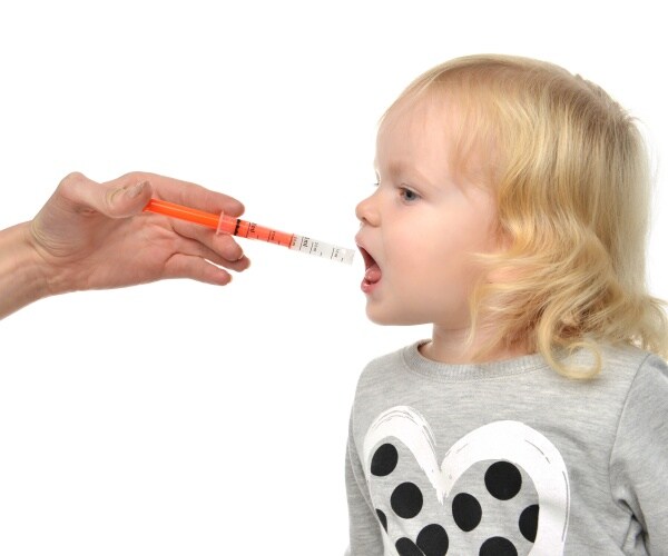 parent giving a child liquid fever-reducing medication in a syringe