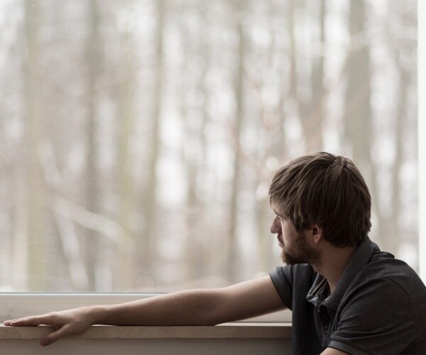 depressed man looking out window