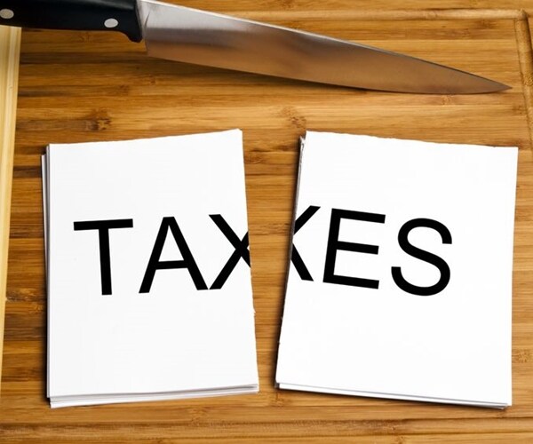 white paper with taxes in black capital letters, cut in two, with big knife nearby