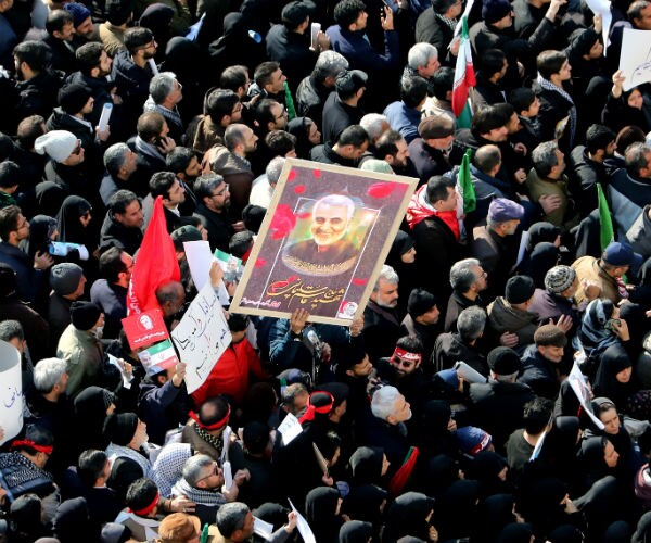 Iranian mourners lift a picture of slain military commander Qasem Soleimani during a funeral procession.
