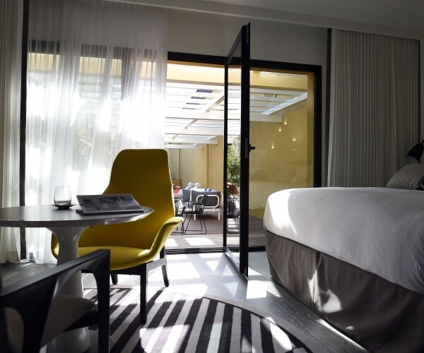 luxury hotel room with a bed and yellow chair at a table