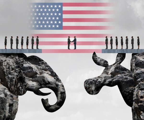 two people shake hands in front of a flag as they stand on rock cutouts of a republican elephant and democratic donkey