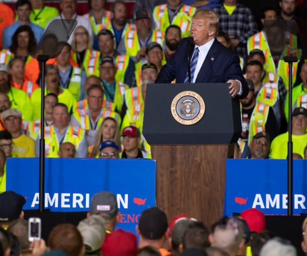 trump speaking with people wearing yellow safety vests in the crowd behind him