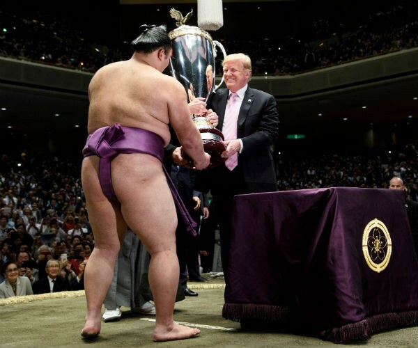 president trump presents a trophy to a sumo wrestler