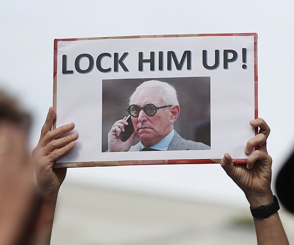 a person hold a sign calling for te court to lock roger stone up