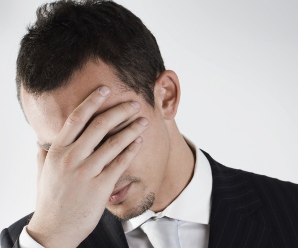 distraught business man in suit with head/face in hands