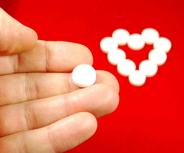 a heart and a hand holding a pill