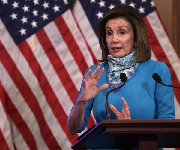nancy pelosi speaks in front of flags