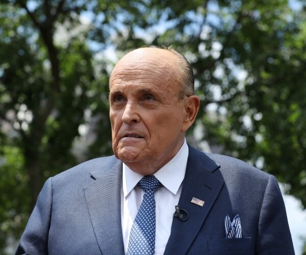 giuliani standing outside wearing a suit and polka dotted blue tie