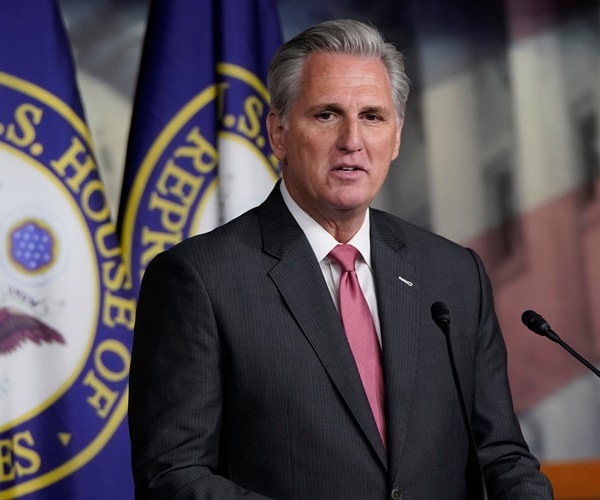 kevin mccarthy stands in front of house of representative and u.s. flags and speaks
