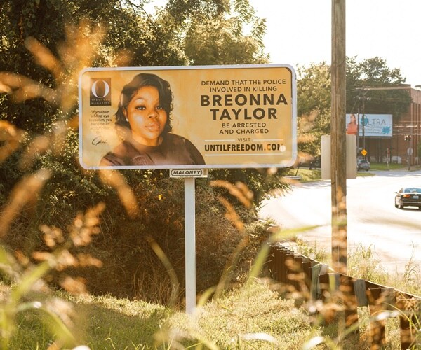 a billboard on the side of a road calls for the arrest of the police who killed breonna taylor