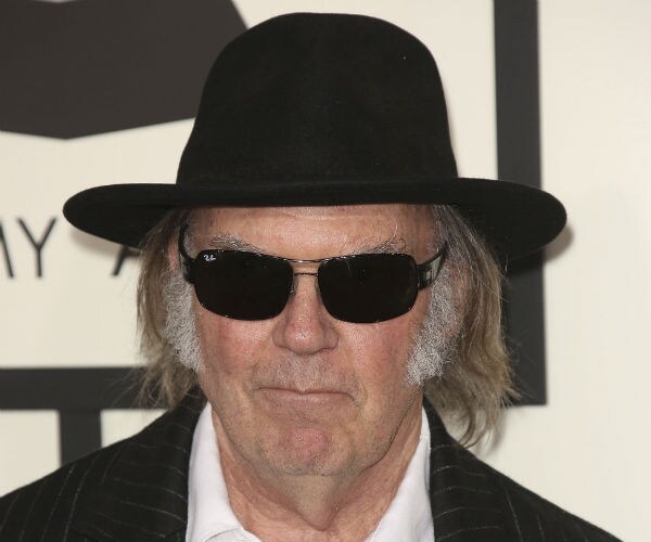 musicial neil young is seen in black hat, sunglasses, white shirt and pinstriped jacket 
