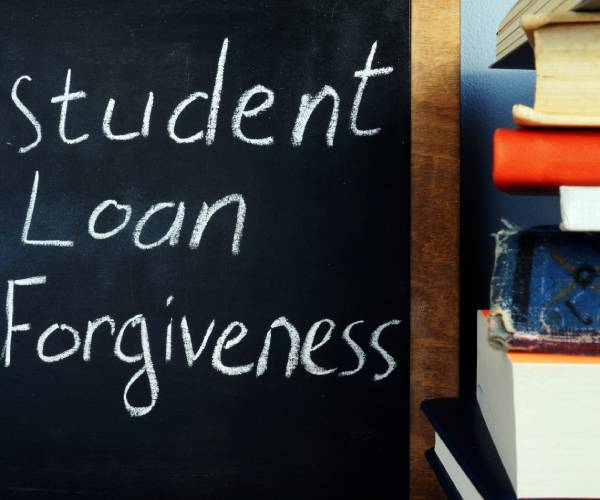 student loan forgiveness written on a blackboard next to a stack of school books