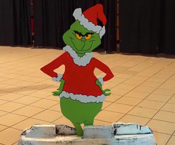 cutout of the the grinch who stole christmas in bright colors standing on floor