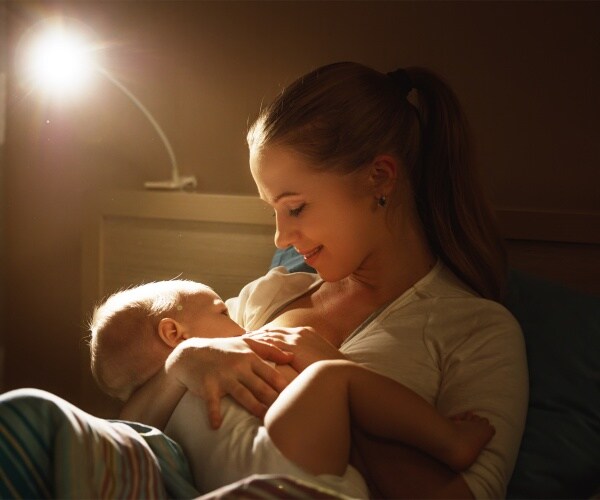 woman in bed breastfeeding baby
