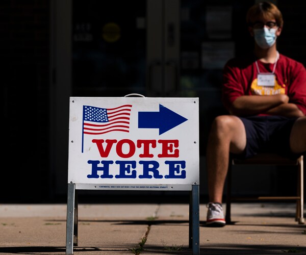 a sign that says vote here in minneapolis
