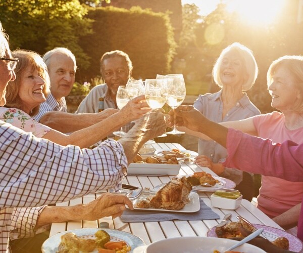 seniors outside having dinner together, smiling, toasting