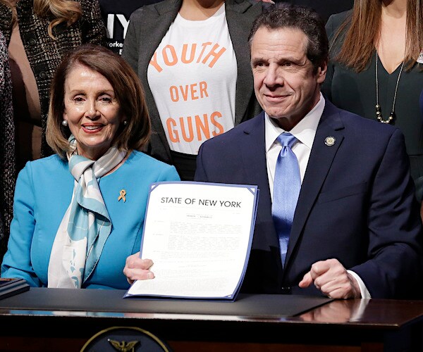 nancy pelosi smiles as new york governor andrew cuomo holds up the signing of the red flag bill