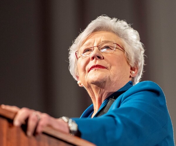 ivey in a blue shirt speaking at a podium