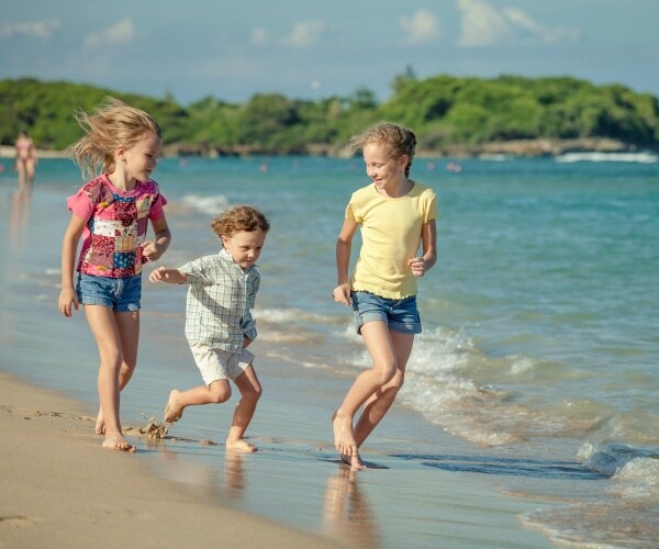 three kids playing on beach on a sunny day