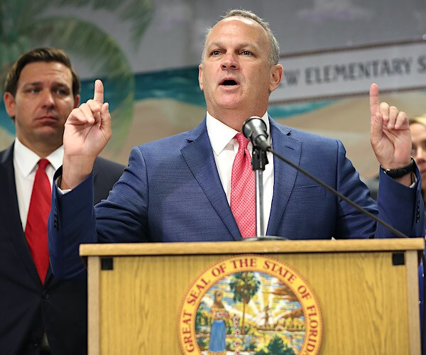 richard corcoran points up with both index fingers during a news conference