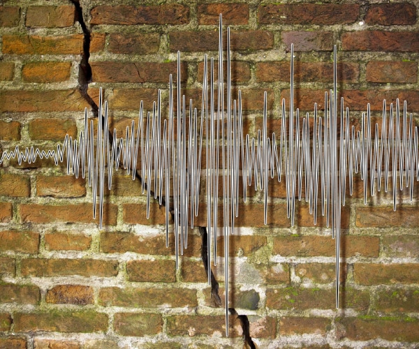 a seismic graph over a cracked brick wall