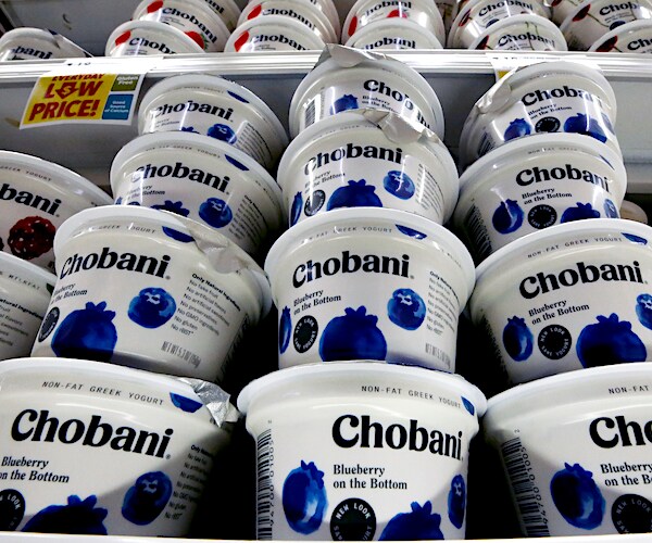 greek yogurt is stacked high on a supermarket shelf