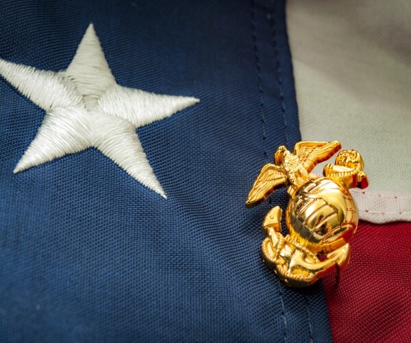 u.s. marine corps pin atop a u.s. flag