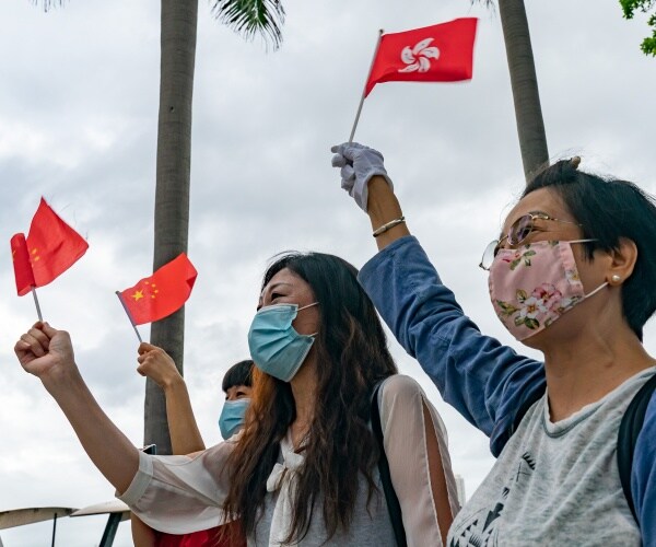 women wearing face masks hold small chinese and hong kong flags
