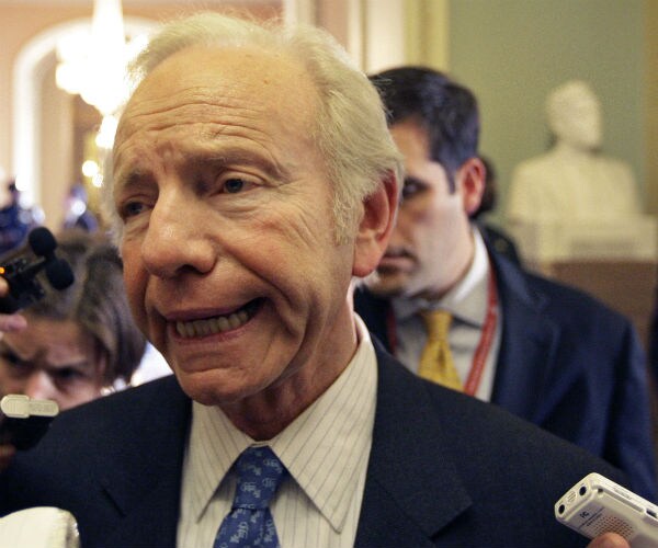 former sen. joe lieberman is shown speaking to reporters with several recorders around him
