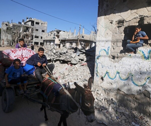 children sit in rubble with guns
