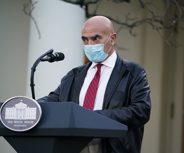 moncef slaoui wears mask and stands behind podium
