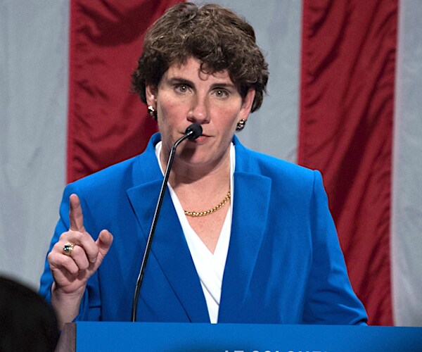 amy mcgrath points with her right index finger while delivering her concession speech in front of a large american flag