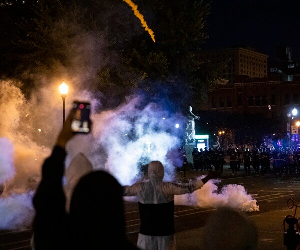 tear gas fills the street in louisville where protesters stand against police