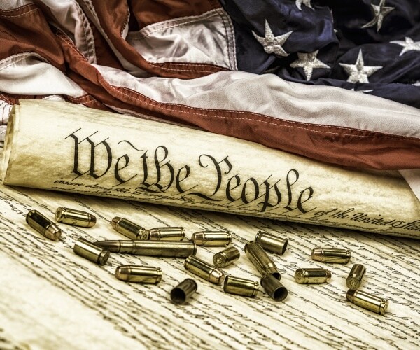 united states constitution rolled up on an american flag with bullets scattered about symbolizing the second amendment