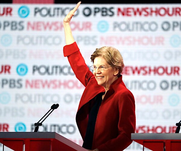 elizabeth warren raises her hand with a smile at the democratic presidential primary debate