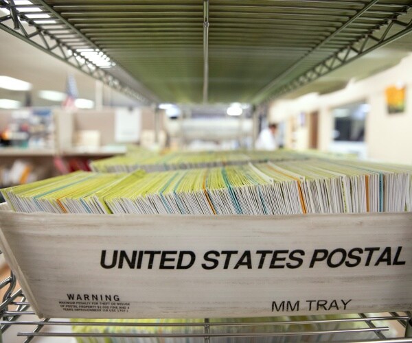 mail in ballots are stacked in a post office bin