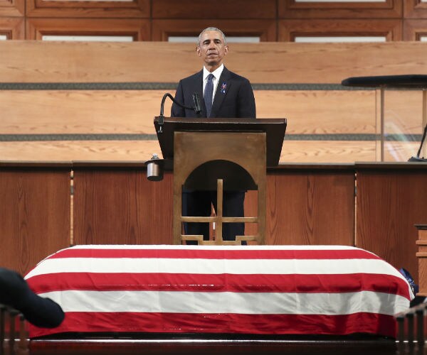former president barack obama stands in a church pulpit over the flag draped coffin of the late rep. john lewis