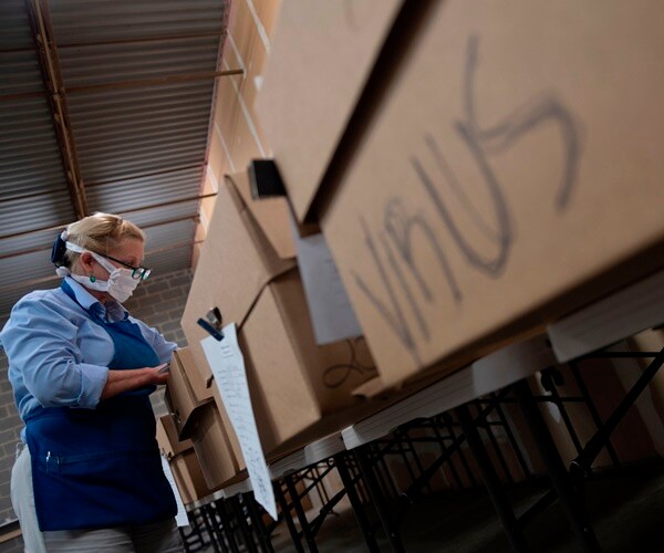 a cremation supervisor checks names of the dead, labeled on cardboard caskets before cremation