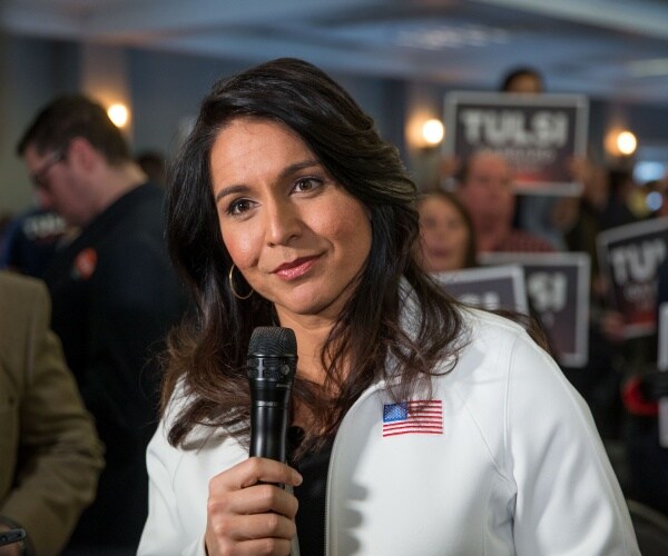 gabbard in a white sweatshirt with a us flag embroidered on it