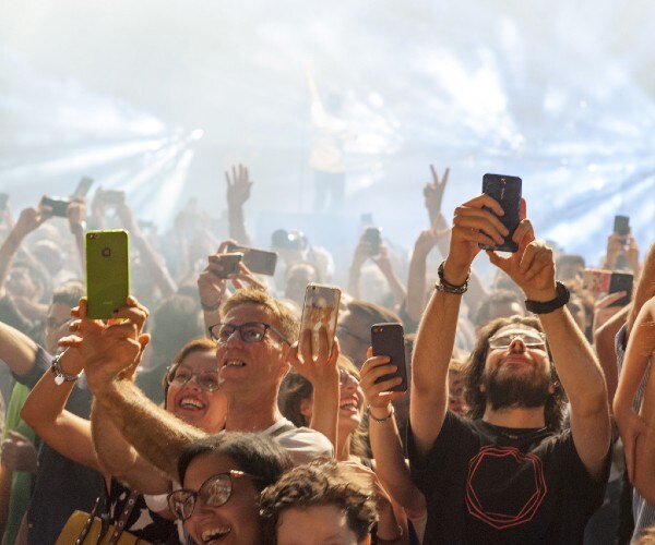 people at a concert taking selfies