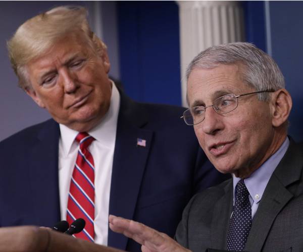 fauci at podium while trump looks on
