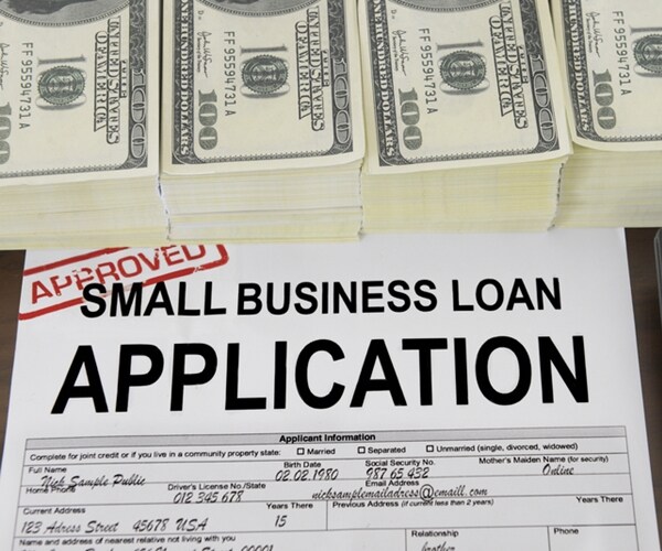 approved small business loan application form and dollar bills