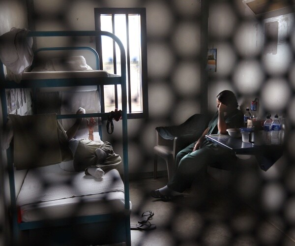 ice detention center is seen with a bunk bed and chair and desk