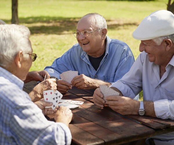 older men playing cards in a park