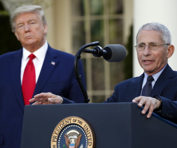dr. anthony fauci speaks in a media briefing as president donald trump looks on