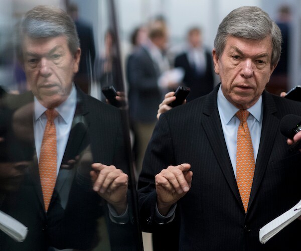 roy blunt gestures and speaks as his reflection is shown in a car window next to him