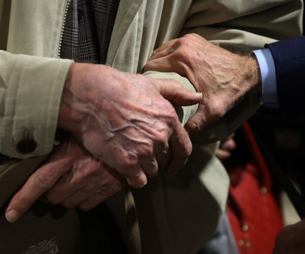 joe biden is shown holding the arm of an elderly man at one of his campaign events